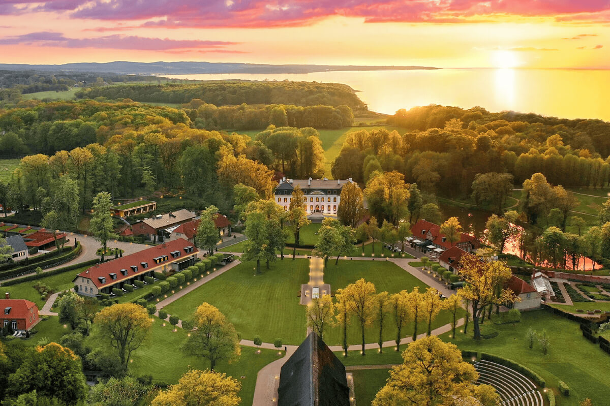 Luftaufnahme des Weissenhaus Private Nature Luxury Resort, umgeben von Bäumen und mit Sonnenuntergang